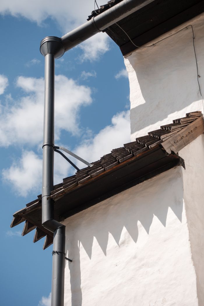 Close-up view of a traditional Finnish building's roof against a clear blue sky, showcasing architectural details.