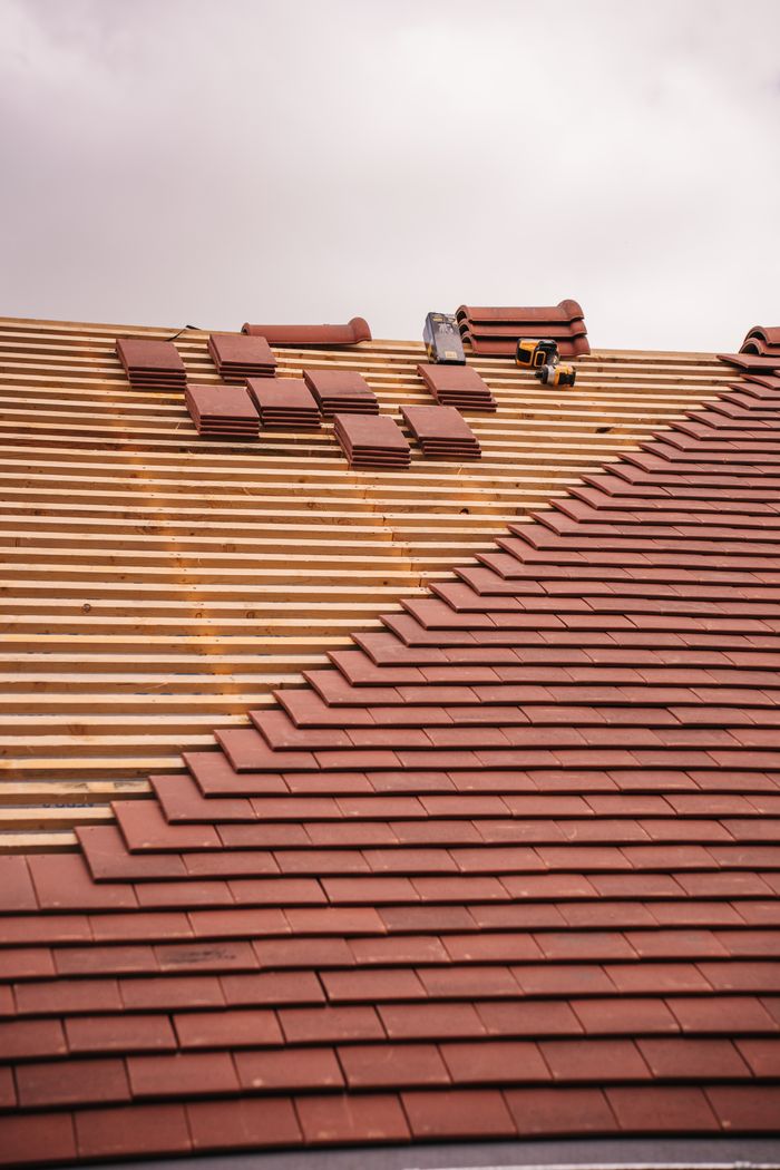 Home Partial installation of a terracotta tile roof on a building in progress.